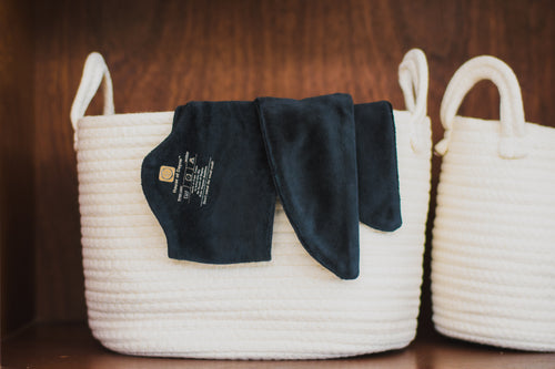 White woven basket with a black garment on a wooden surface